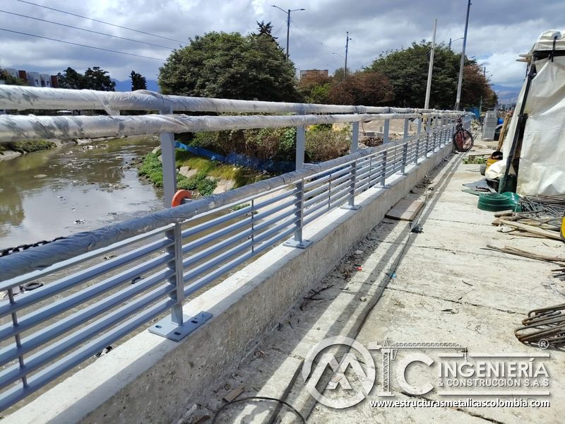 Contemple la baranda gris terminada con tubos protegidos junto al cauce mediante procedimientos seguros en Bogotá, Colombia. Montajes, Ingeniería y Construcción. MIC SAS.