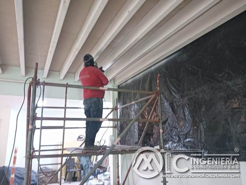 Aplicacion de pintura blanca bajo las vigas del mezzanine metálico en Bogotá y Colombia. Montajes Ingeniería y Construcción. MIC SAS.