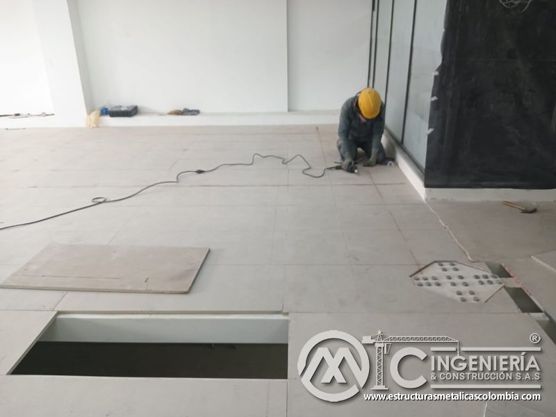 Operario ajusta el piso cerca del cerramiento acristalado del mezzanine metálico en Bogotá y Colombia. Montajes Ingeniería y Construcción. MIC SAS.