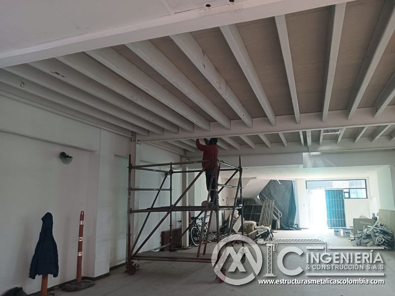 Operario completa acabados de vigas desde andamio del mezzanine metálico en Bogotá y Colombia. Montajes Ingeniería y Construcción. MIC SAS.