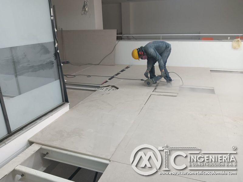 Operario corta placas cerca del borde estructural del mezzanine metálico en Bogotá y Colombia. Montajes Ingeniería y Construcción. MIC SAS.