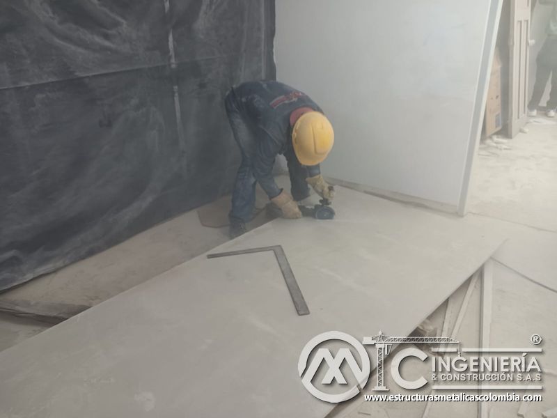 Operario mide y recorta placa junto a protección del mezzanine metálico en Bogotá y Colombia. Montajes Ingeniería y Construcción. MIC SAS.