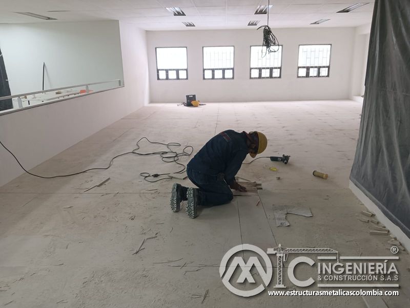Operario rectifica placas del piso superior del mezzanine metálico en Bogotá y Colombia. Montajes Ingeniería y Construcción. MIC SAS.