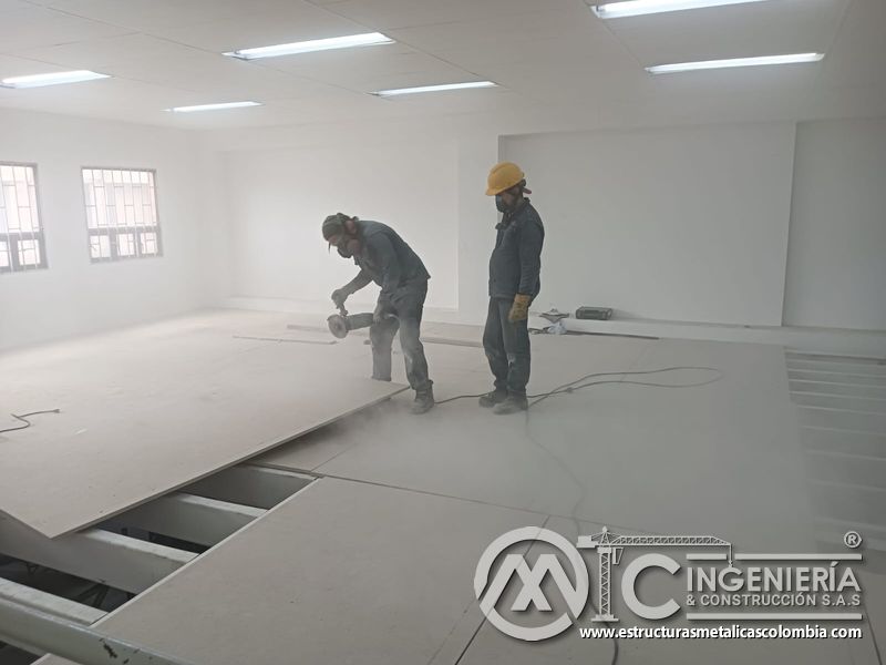Operarios cortan placas para completar el piso del mezzanine metálico en Bogotá y Colombia. Montajes Ingeniería y Construcción. MIC SAS.