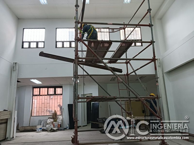 Polipasto eleva perfil blanco hacia la estructura del mezzanine metálico en Bogotá y Colombia. Montajes Ingeniería y Construcción. MIC SAS.