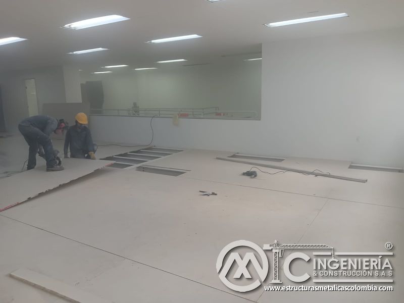 Trabajadores ajustan placas y registros del piso del mezzanine metálico en Bogotá y Colombia. Montajes Ingeniería y Construcción. MIC SAS.