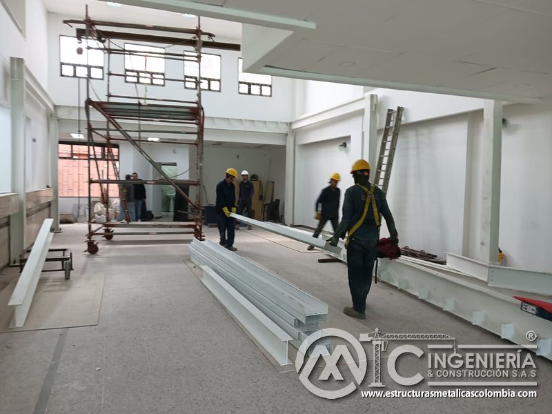 Trabajadores trasladan viga blanca para la estructura del mezzanine metálico en Bogotá y Colombia. Montajes Ingeniería y Construcción. MIC SAS.