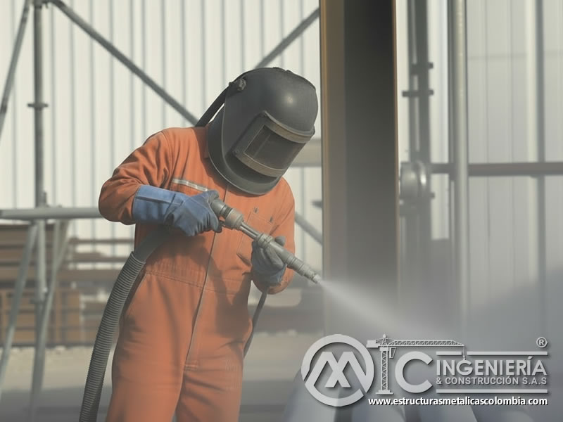 Sandblasting industrial, operario con chorro abrasivo en estructuras metálicas en Bogotá, Colombia. Montajes, Ingeniería y Construcción. MIC SAS.