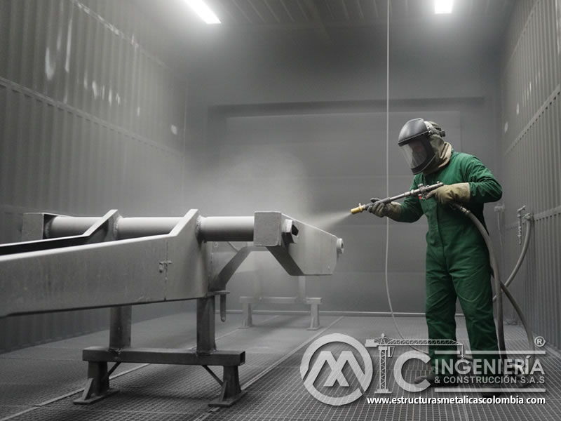 Chorro abrasivo sobre tubería metálica en cabina de sandblasting en Bogotá, Colombia. Montajes, Ingeniería y Construcción. MIC SAS.