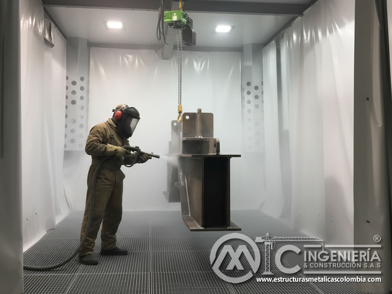 Samblasteo de pieza metálica colgada con cadena en cabina con LED en Bogotá, Colombia. Montajes, Ingeniería y Construcción. MIC SAS.