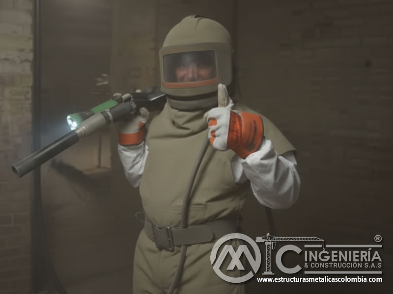 Trabajador con casco tipo burbuja y traje de sandblasting para protección durante labores en planta industrial en Bogotá, Colombia. Montajes, Ingeniería y Construcción. MIC SAS.