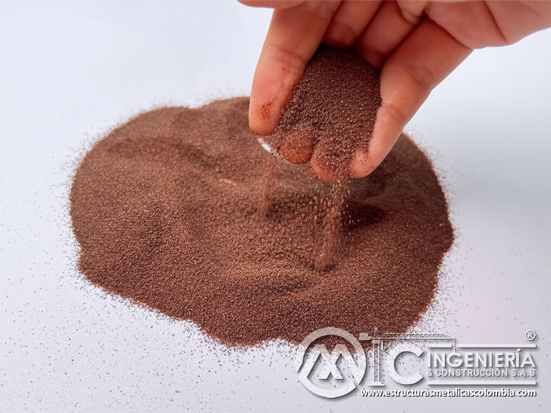 Granate abrasivo fino cayendo sobre montículo mostrando granulometría homogénea. Bogotá, Colombia. Montajes, Ingeniería y Construcción. MIC SAS.