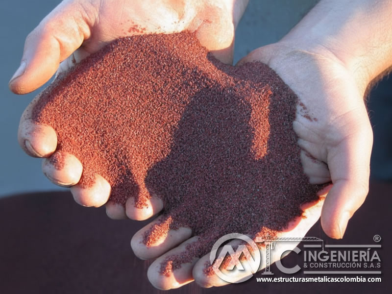 Granate abrasivo rojo fino sostenido en manos para sandblasting. Bogotá, Colombia. Montajes, Ingeniería y Construcción. MIC SAS.