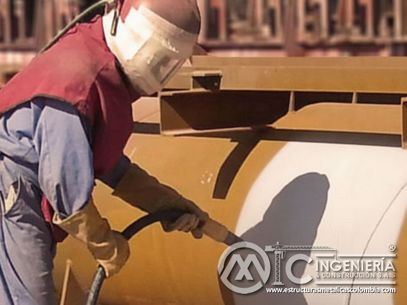 Operario aplicando sandblasting con granate en estructura metálica pintada. Bogotá, Colombia. Montajes, Ingeniería y Construcción. MIC SAS.