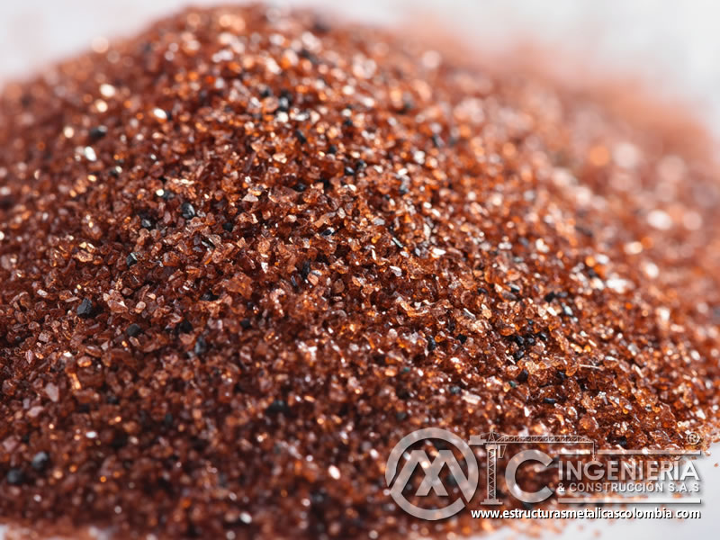 Partículas angulares de granate abrasivo rojizo cobrizo vistas de cerca. Bogotá, Colombia. Montajes, Ingeniería y Construcción. MIC SAS.