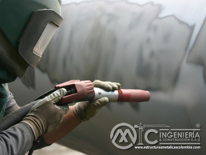Operario con pistola de sandblasting en granallado con plástico. Bogotá, Colombia. Montajes, Ingeniería y Construcción. MIC SAS.